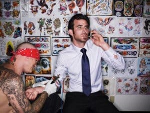 Businessman Talking on Phone While Getting Tattooed